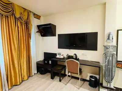 a hotel room with a desk and a tv at K Garden Hotel Parit Buntar in Parit Buntar