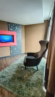 a living room with a chair and a television at Sense Hotel Taiping in Taiping