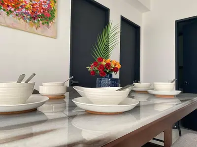 a table with white bowls and a vase of flowers at Urban Suites Georgetown, Penang in Jelutong