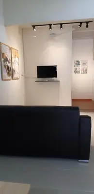 a black couch in a room with paintings on the wall at Ain's Homestay Muslim friendly Kuala Kubu Bharu in Kuala Kubu Baharu