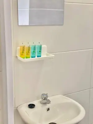 a bathroom sink with two cups on a shelf at Rumah Inap Che'Gu Baha in Teluk Intan