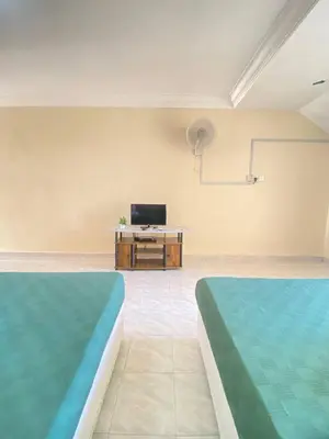 two beds in a room with a tv and a table at Teluk Batik Holiday Apartment in Lumut