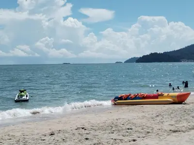 a inflatable boat on the beach with people in the water at Teluk Batik Holiday Apartment in Lumut