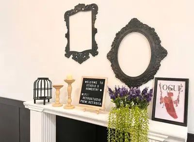 two mirrors on a fireplace mantle with flowers and pictures at Studio S Conceptual Homestay Station 18 - Ipoh in Ipoh