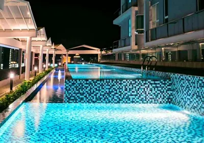 a swimming pool at night with blue tiles at Ipoh City Modern Homestay Octagon 5-6 pax Apartment Suite Free Parking by City Home Empire in Ipoh