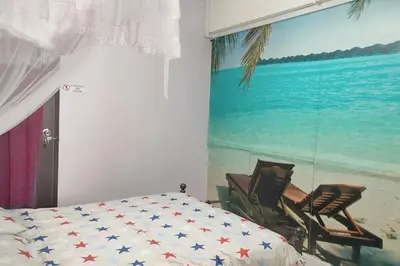 a bedroom with a bed and two chairs next to a painting at Comfy Home Near to Penang Hill in Ayer Itam