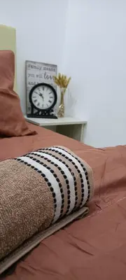a bed with a clock and a blanket on it at QM_Homestay Bagan Serai in Bagan Serai