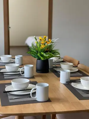 a wooden table with white dishes and a vase of flowers at Secret Garden @ Cameron Centrum in Brinchang
