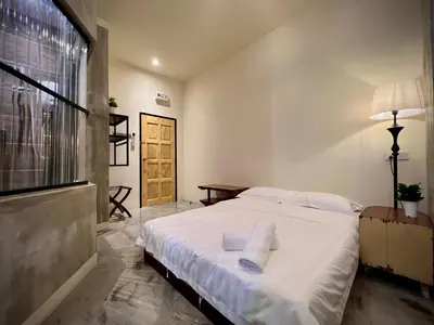 a bedroom with a bed with white sheets and a window at DoSomething Guest House 3 in Ipoh