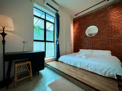 a bedroom with a brick wall and a bed and a desk at DoSomething Guest House 8 in Ipoh