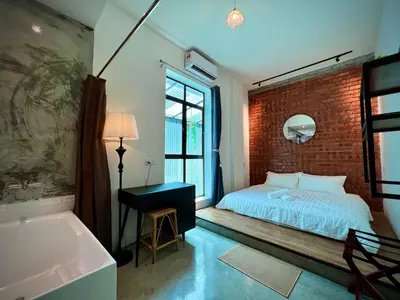 a bedroom with a brick wall and a bed and a tub at DoSomething Guest House 8 in Ipoh
