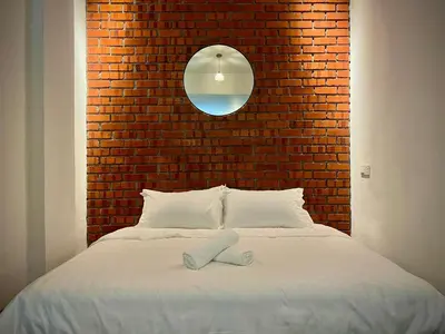 a bedroom with a bed with a brick wall at DoSomething Guest House 8 in Ipoh