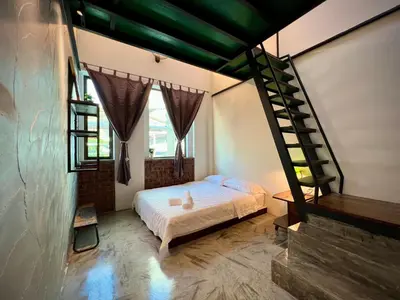 a bedroom with a bed and a spiral staircase at DoSomething Guest House 1 in Ipoh