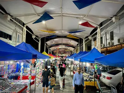 a group of people walking through a market with blue umbrellas at DoSomething Guest House 1 in Ipoh