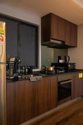 a kitchen with wooden cabinets and a stove top oven at Luxury Seaview Projector Lounge by The Only Bnb in Tanjong Tokong