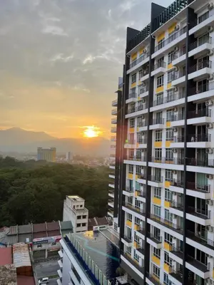 a tall building with the sunset in the background at JS Ipoh Homestay @ The Majestic Ipoh in Ipoh