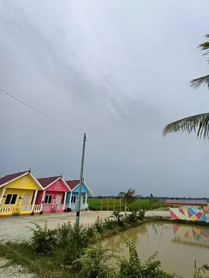a row of colorful houses next to a body of water at Laman D'Arni in Sungai Besar