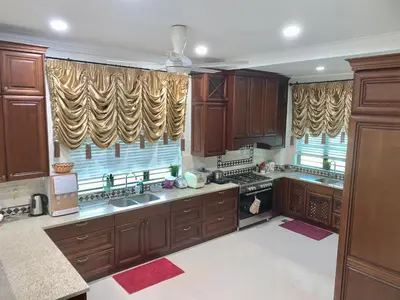 a large kitchen with wooden cabinets and counters at Puncak Villa 10-20pax in Kuala Kangsar