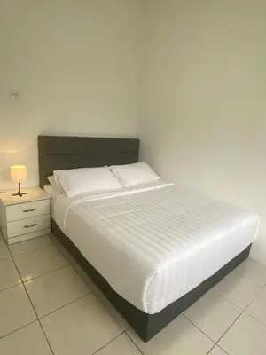 a bedroom with a white bed with a nightstand and a bed sidx sidx sidx at Biella Homestay Apartment for Muslim in Tanah Rata
