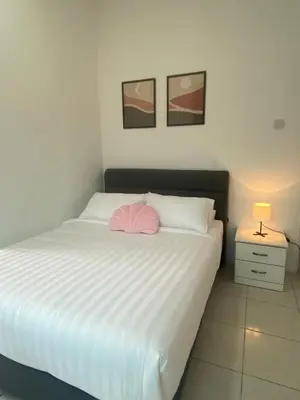 a bedroom with a white bed with a pink pillow at Biella Homestay Apartment for Muslim in Tanah Rata
