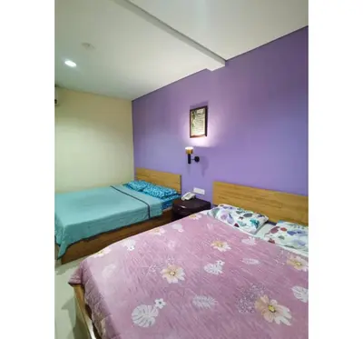 two beds in a room with purple walls at Hotel O Pavilion Inn Hotel in Lumut