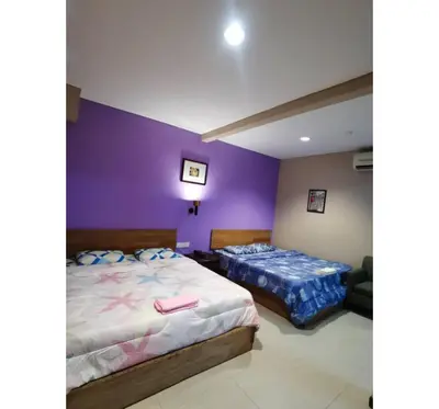 two beds in a room with purple walls at Hotel O Pavilion Inn Hotel in Lumut