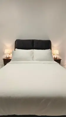 a large white bed with two lamps on two tables at Paddy Villea Inn SPT Penang in Permatang Pauh