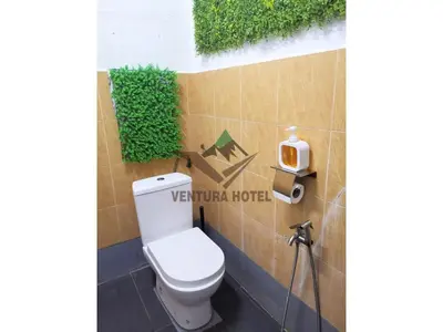 a toilet in a bathroom with a sign on the wall at Ventura Hotel and Tours in Gua Musang