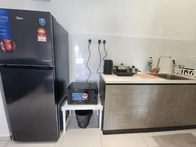 a kitchen with a black refrigerator and a sink at The Horizon - Ipoh in Ipoh