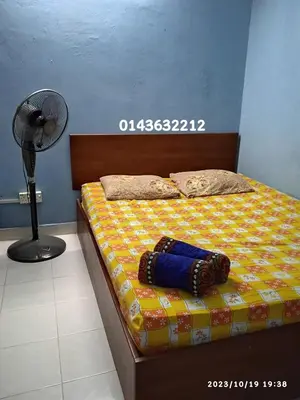 a bed with a pillow and a fan next to it at Ekaira homestay in Tambun