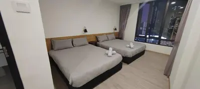 a room with two beds and a couch and a window at Utopia Homestay @ Cameron Centrum in Cameron Highlands