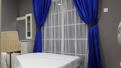 a bedroom with a bed and a blue curtain at Champs Elysees in Kampar