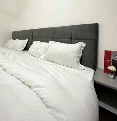 a large white bed with a black headboard and white pillows at Ipoh Cozy Homestay by Comfort Home in Ipoh