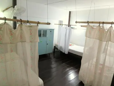 a bedroom with a bed and white curtains in it at Pangkor Guesthouse SPK in Pangkor