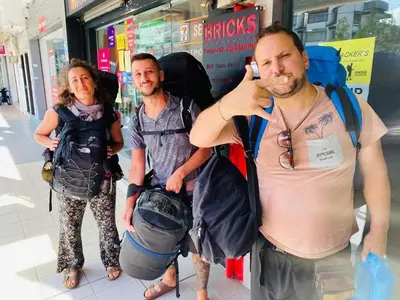 three people standing in front of a store talking on a cell phone at BRICKS Cameron Hostel in Tanah Rata