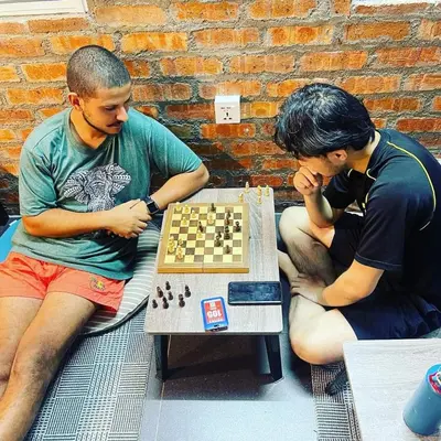 two men sitting on the floor playing chess at BRICKS Backpackers Sleepbox in Tanah Rata