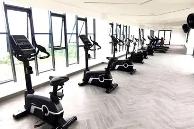 a row of exercise bikes in a gym with windows at Urbanite Premier Suite - Horizon Ipoh by Grab A Stay in Ipoh