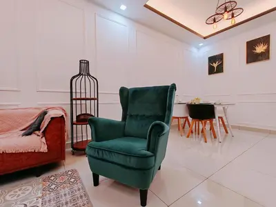 a living room with a green chair and a table at WHITE ON HOMESTAY CAMERON BY ICOLOR in Tanah Rata