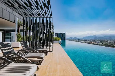 a row of chairs sitting on the edge of a swimming pool at JOMSTAY - Horizon Suites Ipoh Town Skypool in Ipoh
