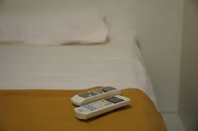 two remote controls sitting on the edge of a bed at Taiping Modern Home in Kamunting