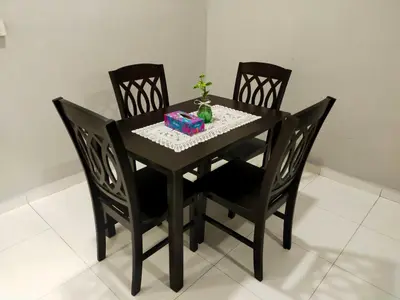 a black dining room table with four chairs and a present at Homestay Manitha in Seri Manjung