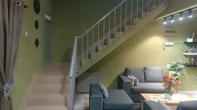 a living room with a staircase with a couch and chairs at Homestay Rezeki Batu Gajah in Batu Gajah