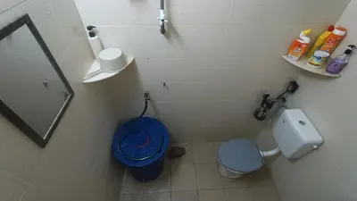 a bathroom with a toilet and a blue bucket at Homestay Rezeki Batu Gajah in Batu Gajah