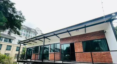 a building with glass windows and a brick building at Big Dreams Garden Stay in Tanah Rata