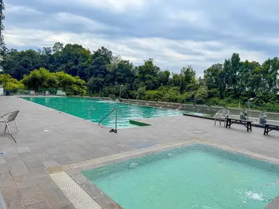 a large pool of water with chairs and a table at Taiping City View 3BR Condo near Lake Garden with Sunset View & Swimming Pool, Free Netflix WiFi in Taiping
