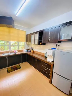 a kitchen with wooden cabinets and a white refrigerator at Qaseh Homestay Cameron Highlands 3 in Brinchang