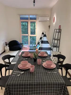 a table with pink dishes on it in a living room at EE's Sunset House - Homestay 3 min walk to beach in Batu Ferringhi