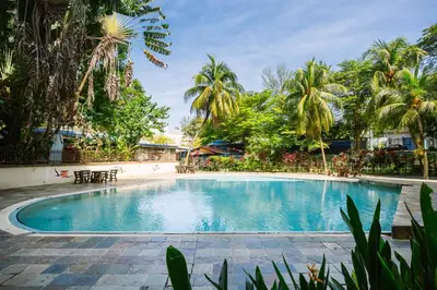 a swimming pool in a resort with palm trees at EE's Sunset House - Homestay 3 min walk to beach in Batu Ferringhi