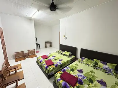 a bedroom with two beds and a table and chairs at Muhibbah Homestay in Sungai Siput
