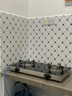 a stove top in a kitchen with a tiled wall at Rezeki indah Hstay self check in in Bukit Mertajam